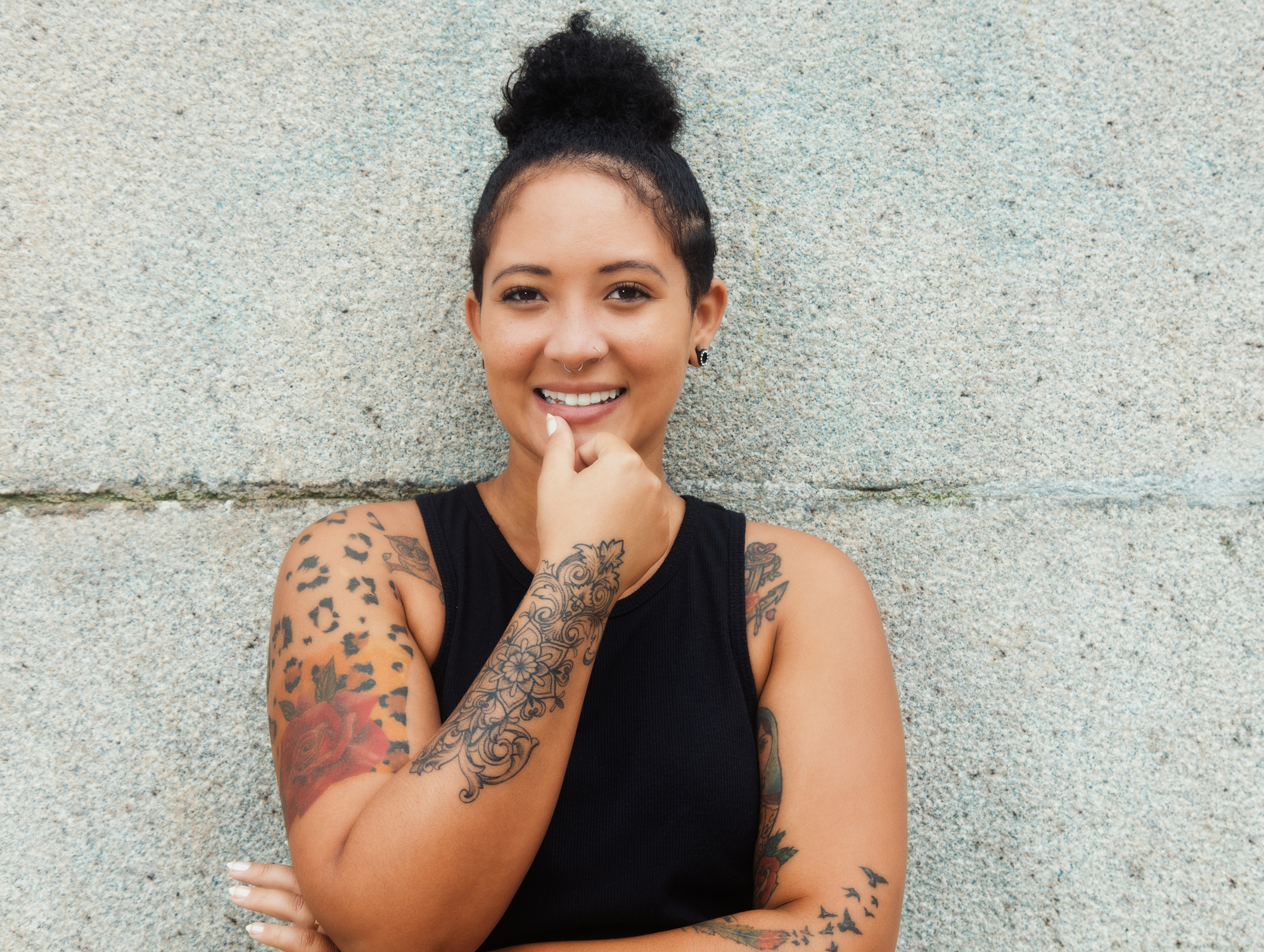 Laughing hipster girl with tattoos and piercing in urban style